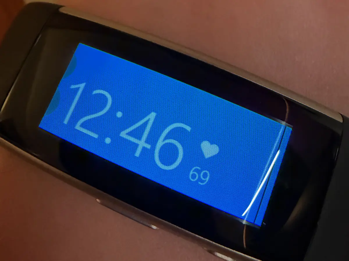 A Microsoft Band 2 on a wrist, its blue watch face showing 12:46 and a heart rate of 69
